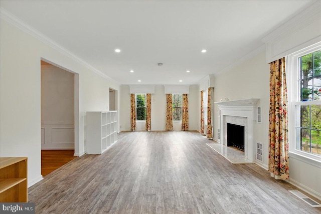 unfurnished living room with a fireplace, wood finished floors, visible vents, and ornamental molding