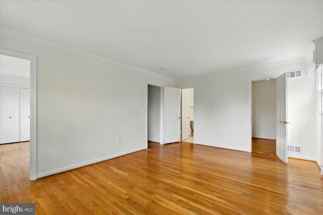 spare room with ornamental molding, visible vents, and light wood-type flooring