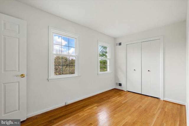 unfurnished bedroom with light wood-style floors, visible vents, and baseboards