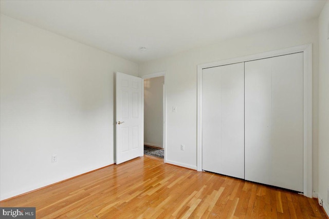 unfurnished bedroom with light wood-style flooring and a closet