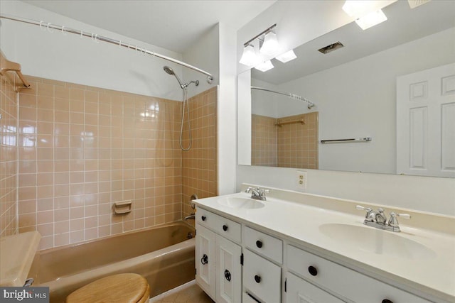 bathroom featuring toilet, a sink, tub / shower combination, and double vanity
