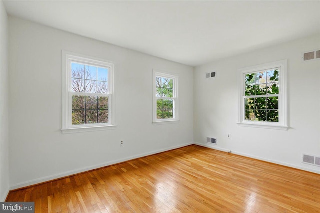 empty room with baseboards, light wood-style floors, and visible vents