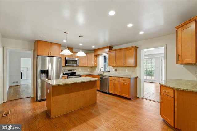 kitchen featuring a sink, backsplash, appliances with stainless steel finishes, light stone countertops, and visible vents