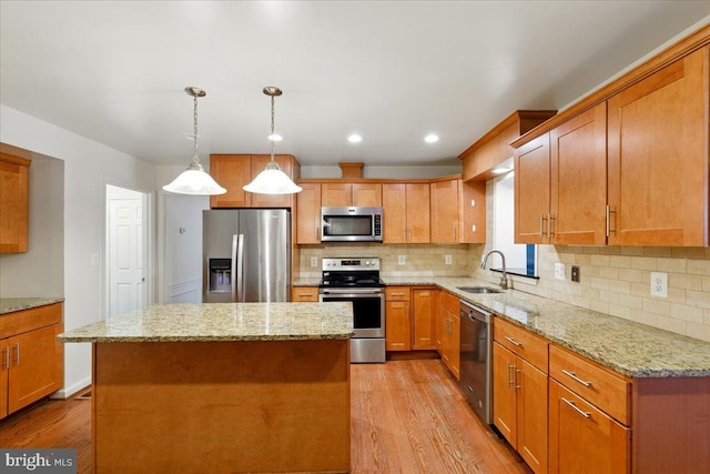 kitchen featuring light wood-style flooring, appliances with stainless steel finishes, decorative backsplash, and a sink