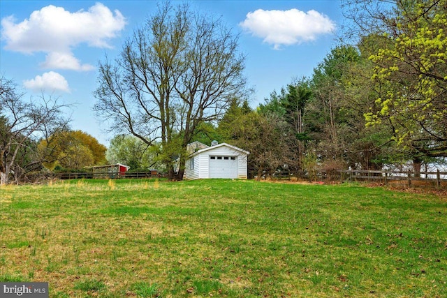 view of yard with a garage, an outbuilding, and fence