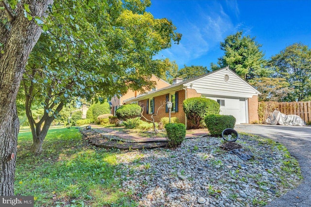 view of home's exterior featuring a garage, brick siding, aphalt driveway, and fence
