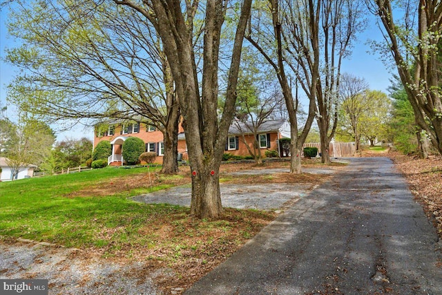 view of front of property with fence, a front lawn, and driveway