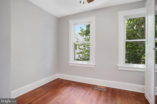 empty room featuring ceiling fan, a healthy amount of sunlight, and dark hardwood / wood-style floors