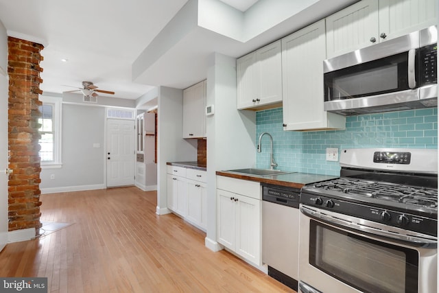 kitchen with white cabinets, stainless steel appliances, sink, backsplash, and ceiling fan