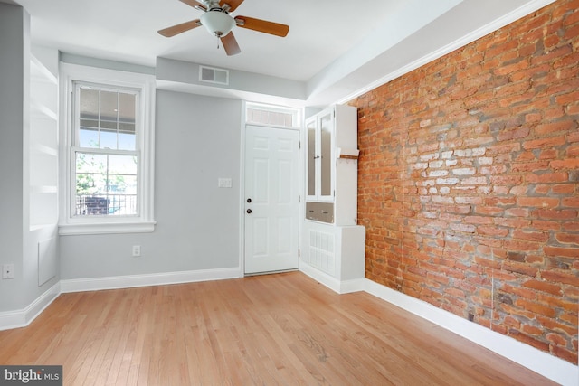 empty room with light hardwood / wood-style floors, brick wall, and ceiling fan