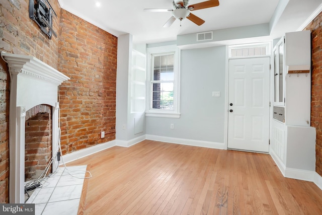 entryway with ceiling fan, brick wall, and light hardwood / wood-style flooring