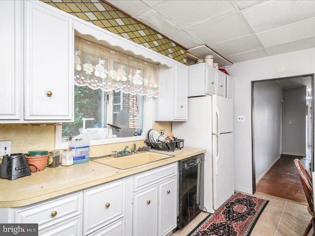 kitchen featuring a drop ceiling, dishwasher, white cabinets, and sink