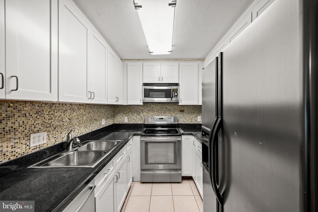 kitchen featuring stainless steel appliances, sink, light tile patterned floors, a textured ceiling, and white cabinetry