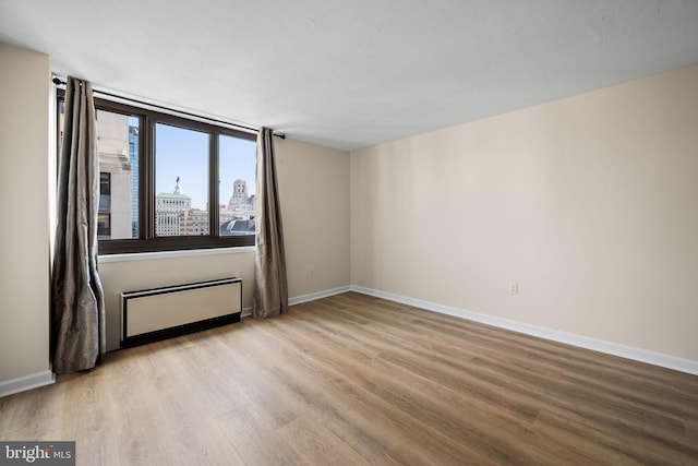 spare room featuring radiator and light hardwood / wood-style flooring