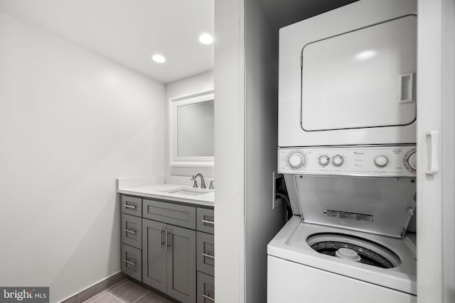 washroom with tile patterned flooring, stacked washer / drying machine, and sink