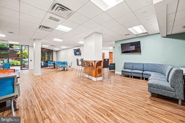 living room featuring a drop ceiling and light hardwood / wood-style flooring