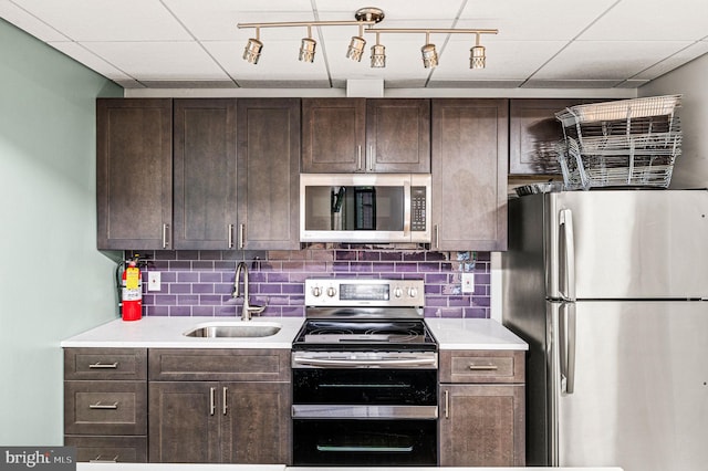 kitchen with dark brown cabinets, rail lighting, appliances with stainless steel finishes, and sink