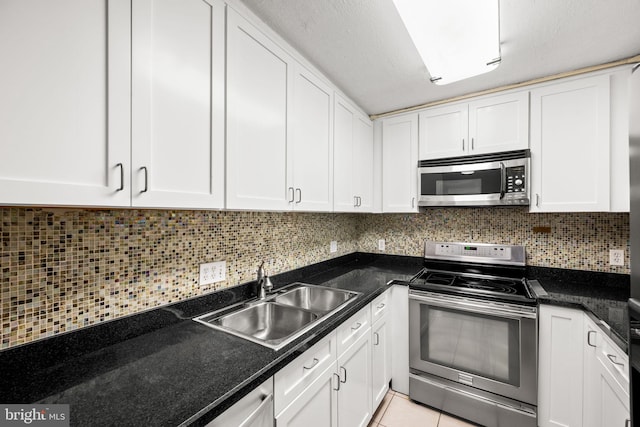 kitchen featuring appliances with stainless steel finishes, light tile patterned flooring, white cabinetry, and sink