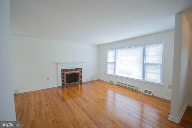 unfurnished living room with baseboard heating, a fireplace, and hardwood / wood-style flooring