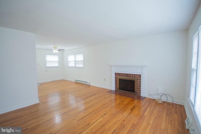 unfurnished living room featuring light wood-type flooring, baseboard heating, a fireplace, and ceiling fan