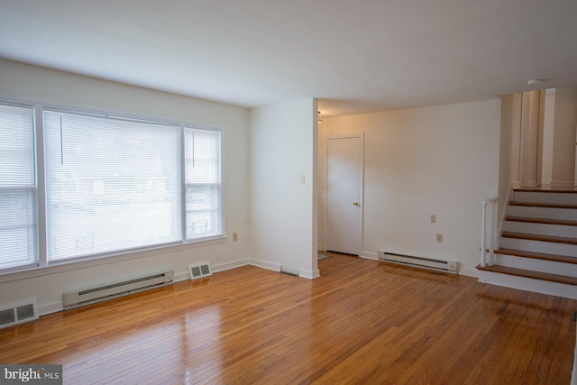 empty room featuring a baseboard heating unit and hardwood / wood-style flooring