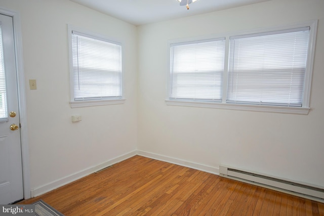 spare room featuring a baseboard heating unit and wood-type flooring