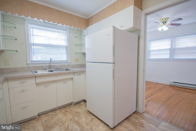 kitchen featuring baseboard heating, white cabinets, white refrigerator, sink, and ceiling fan