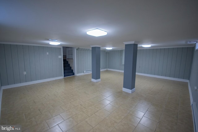 basement featuring baseboard heating, crown molding, and wood walls