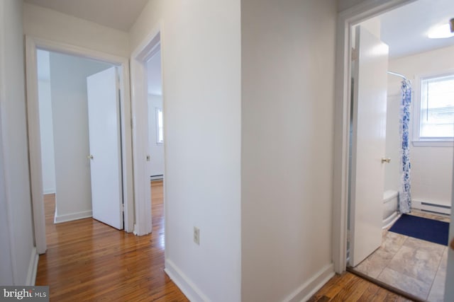 hallway with baseboard heating and light hardwood / wood-style floors