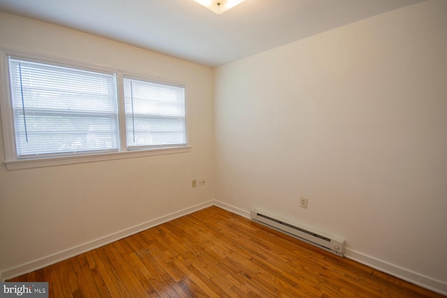 unfurnished room with a baseboard radiator and hardwood / wood-style floors