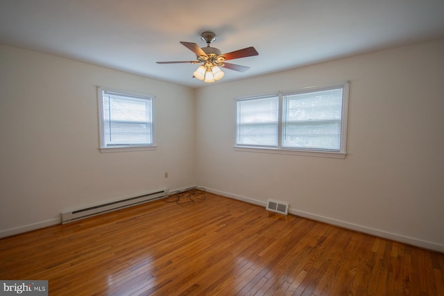 spare room with ceiling fan, wood-type flooring, and a baseboard heating unit