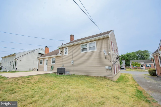 rear view of house with a lawn, central air condition unit, and a patio