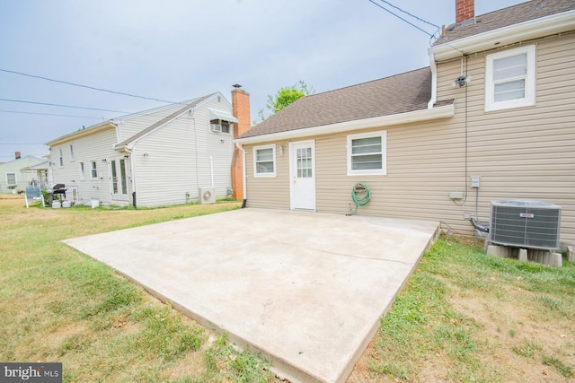 rear view of house with a lawn, central air condition unit, and a patio