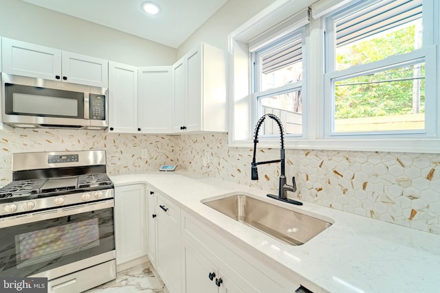 kitchen with light stone countertops, sink, white cabinets, and appliances with stainless steel finishes