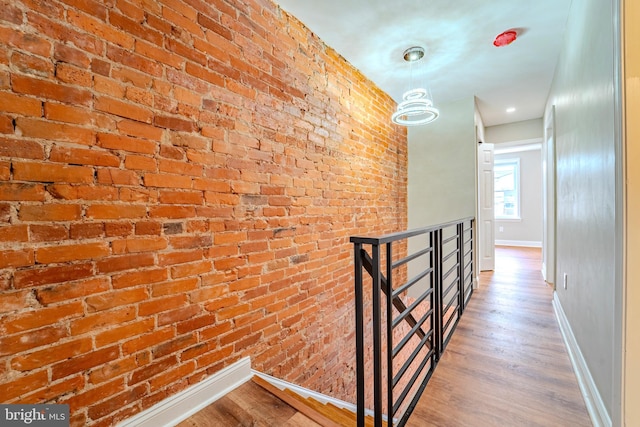 hallway featuring wood-type flooring and brick wall