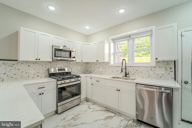 kitchen featuring stainless steel appliances, backsplash, white cabinetry, and sink