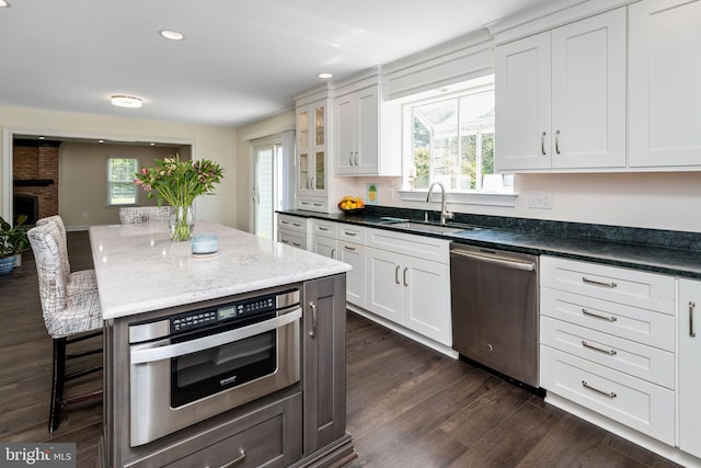 kitchen with white cabinets, stainless steel dishwasher, sink, and a fireplace