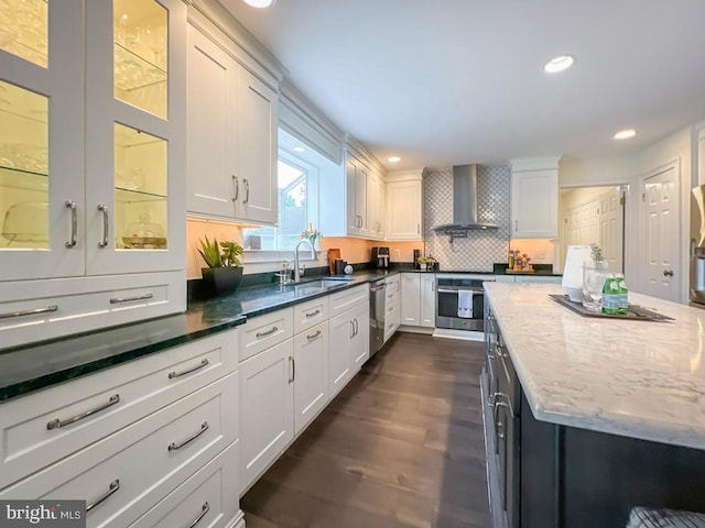 kitchen with sink, white cabinets, appliances with stainless steel finishes, and wall chimney exhaust hood