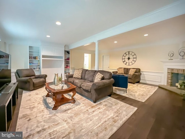 living room with hardwood / wood-style floors, ornamental molding, and a fireplace