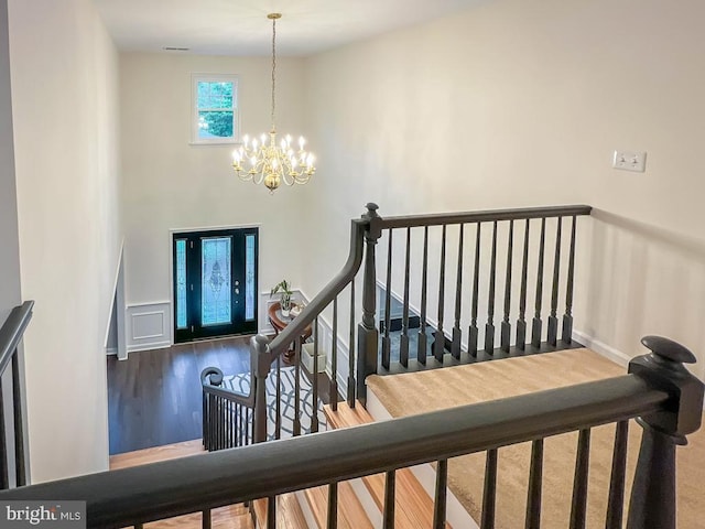 stairs with wood-type flooring and a chandelier