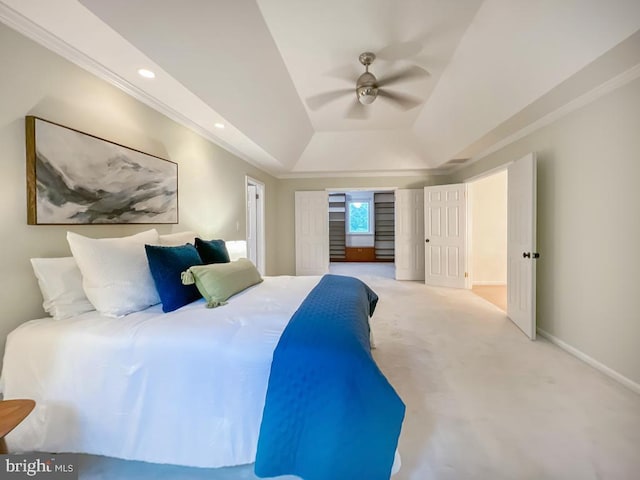 bedroom with light carpet, ceiling fan, and a tray ceiling