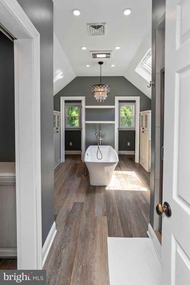 bathroom featuring lofted ceiling, plenty of natural light, a bathing tub, and hardwood / wood-style flooring