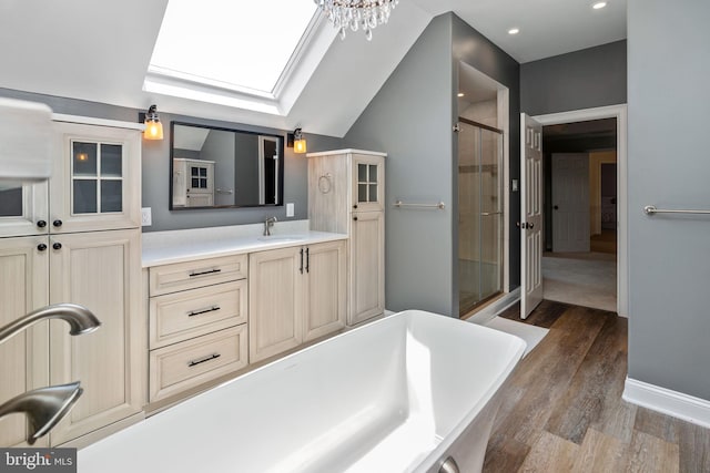 bathroom featuring separate shower and tub, vanity, wood-type flooring, and lofted ceiling with skylight