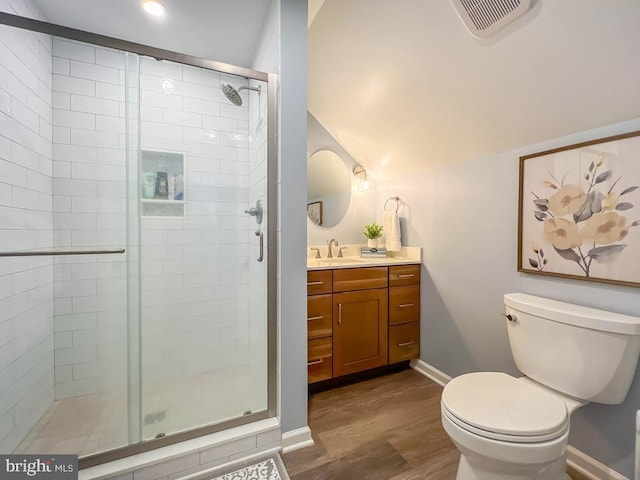 bathroom with hardwood / wood-style flooring, toilet, vanity, and an enclosed shower