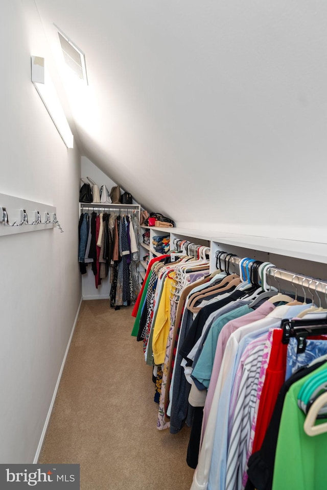 spacious closet with light colored carpet and vaulted ceiling