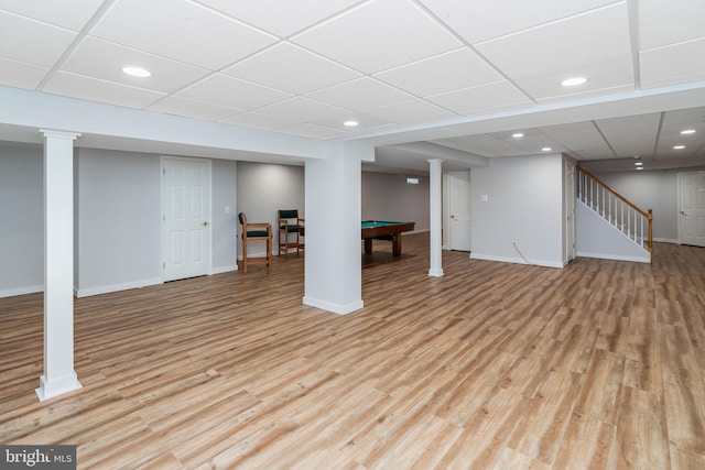 basement with a paneled ceiling, pool table, and light hardwood / wood-style flooring