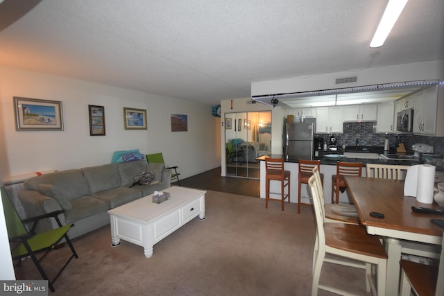 living room featuring dark carpet and a textured ceiling