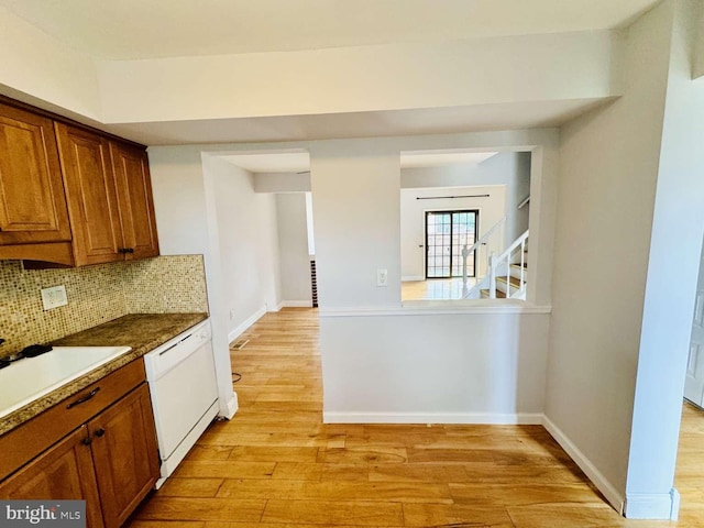 kitchen with white dishwasher, sink, decorative backsplash, and light hardwood / wood-style flooring