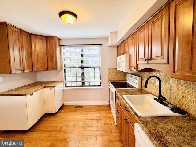 kitchen featuring light wood-type flooring, backsplash, sink, and white appliances