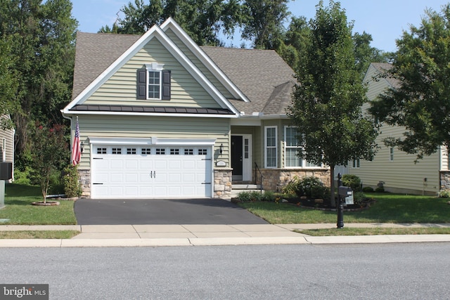 craftsman-style house featuring stone siding, driveway, a shingled roof, and a front yard